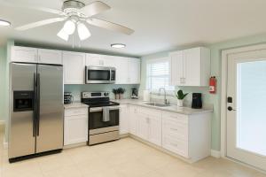 a kitchen with white cabinets and a ceiling fan at Charming 1BR Canal Front Retreat in Naples
