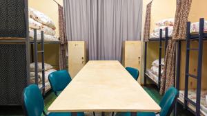 a table and chairs in a room with bunk beds at Sun Hostel in Almaty