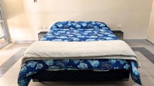 a bed with a blue and white blanket on it at Turquesa in Villa Mercedes