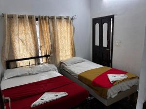 two twin beds in a room with a window at Hotel Guest Inn in Mysore