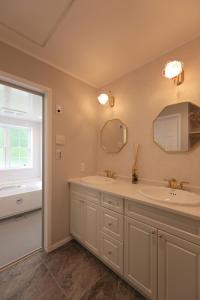 Un baño con dos lavabos y una gran ventana. en 軽井沢の森に佇む英国様式白の宮殿 薪ストーブある5ldk ポーラーリゾート軽井沢ミューズ, en Naganohara