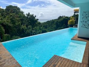 a swimming pool with blue water and trees at STUDIO O'KALM in Le Gosier
