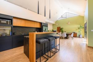 a kitchen with black cabinets and a bar with stools at Black Pool Situé à SANUR 4BR in Sanur