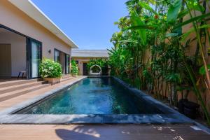 a swimming pool in front of a house at Black Pool Situé à SANUR 4BR in Sanur