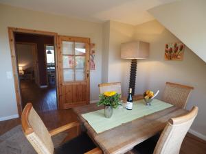 une salle à manger avec une table en bois avec des fleurs et une lampe dans l'établissement Süderhof Apartment 1, à Keitum