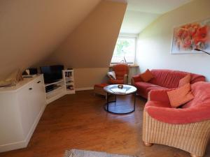 un salon avec un canapé rouge et une table dans l'établissement Süderhof Apartment 1, à Keitum