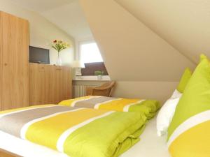 - 2 lits dans une chambre avec des draps jaunes et gris dans l'établissement Süderhof Apartment 1, à Keitum