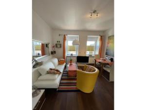 ein Wohnzimmer mit einer weißen Couch und einem gelben Stuhl in der Unterkunft Comfort Apartment House Regini in Norderney