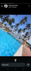 a picture of a pool with palm trees on a screen at Alquilo apartamento vacacional en tucacas in Tucacas