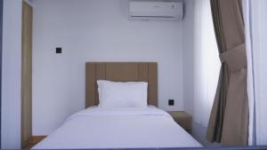 a bed in a small room with a white bedsheet at Villa Dalia Puncak ACC9-18 in Cikujang