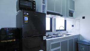 a kitchen with a black refrigerator and a sink at Villa Dalia Puncak ACC9-18 in Cikujang