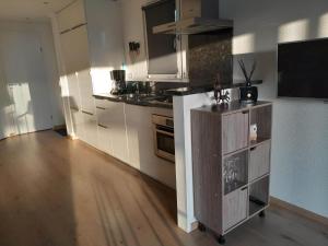 a kitchen with white cabinets and a television in it at Chalet Rosa Livita in De Heen