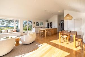 a kitchen and living room with a table and chairs at Palm Beach Retreat - Be My Guest Waiheke in Waiheke Island