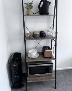 a shelf with a microwave and plates and a printer at Secluded Lake Ōkāreka Studio Views, Spa, Deck in Rotorua in Rotorua
