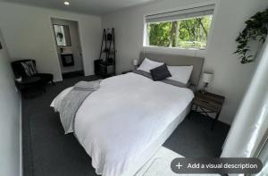 a bedroom with a large white bed with a window at Secluded Lake Ōkāreka Studio Views, Spa, Deck in Rotorua in Rotorua