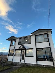 a white house with windows and a blue sky at The White House Hostel in Puerto Natales