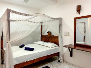 a bedroom with a canopy bed and a mirror at Mermaid Inn in Mirissa
