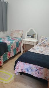 two beds in a room with a mirror and a table at Casa grande em arapongas in Arapongas