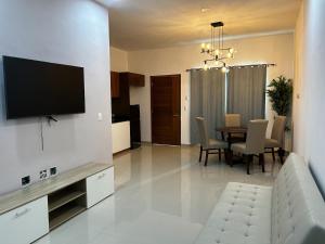 sala de estar con mesa y TV en la pared en Dto amplio cerca de playa, en Mazatlán