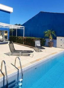 two chairs sitting next to a swimming pool at Casa do Aconchego Quadra 28 in Bertioga
