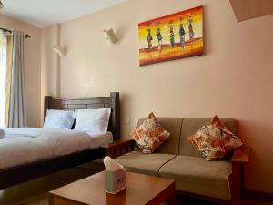 a hotel room with a bed and a couch at Furnished Studio Apartment in Nairobi West in Nairobi