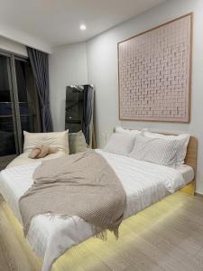 a bedroom with a large white bed and a picture on the wall at Sea Breeze Apartment The Sóng-View Biển & Hồ Bơi Resort Vũng Tàu in Vung Tau