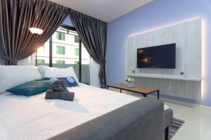 une chambre avec un grand lit avec une télévision au mur dans l'établissement Cozy JB Suasana 15 Suite City Views, à Johor Bahru