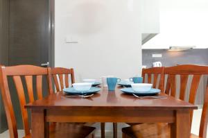 une table en bois avec des bols et des assiettes dans l'établissement Cozy JB Suasana 15 Suite City Views, à Johor Bahru