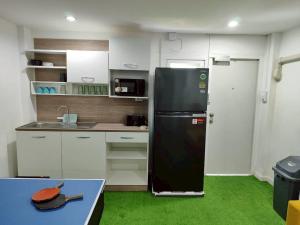 een keuken met een zwarte koelkast in een kamer bij Banana Bunkhouse Hostel in Rawai Beach