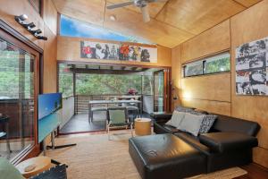 a living room with a leather couch and a television at Pandanus Retreat in Point Lookout