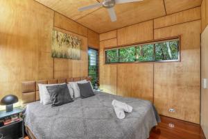 a bedroom with a bed with wooden walls and a window at Pandanus Retreat in Point Lookout