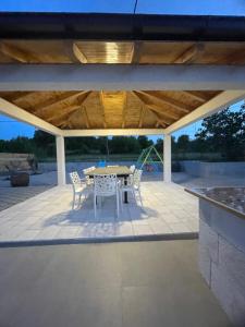 a patio with a table and chairs under a roof at Mediterranean 5 rooms house with pool in Ramljane