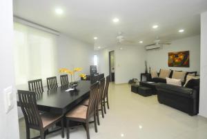 a dining room and living room with a black table and chairs at Phenomenal Location Near Beach & 5th with Stunning Roof Pool in Playa del Carmen