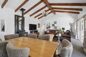 a living room with a wooden table and chairs at Fishermans Cottage - Waikanae Beach in Waikanae