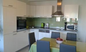 a kitchen with white cabinets and a table with a bowl of fruit at Apartment Mery in Trogir