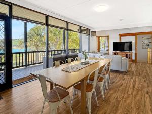 Una sala de estar con una gran mesa y sillas de madera. en Lakefront Palms, en Bonnie Doon