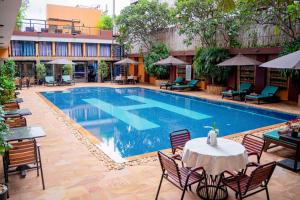 a swimming pool with a table and chairs next to a building at Sokchea Angkor Hotel in Siem Reap
