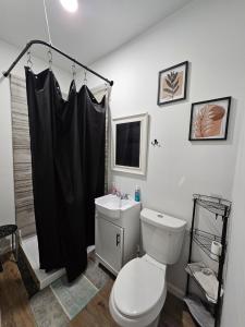 a bathroom with a toilet and a black shower curtain at Maple Manor Private in Saint Louis