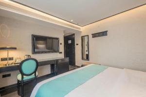 ein Schlafzimmer mit einem Bett, einem Schreibtisch und einem Fernseher in der Unterkunft Xana Hotelle·Nanchang Bayi Square Metro Station in Nanchang
