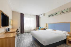 a hotel room with a large bed and a television at City Comfort Inn Deyang Shifang Yonghu Park in Deyang