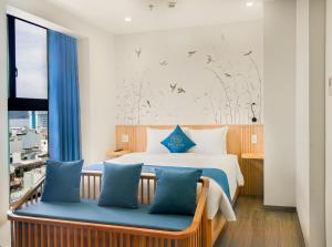 a bedroom with a bed with blue pillows and a window at Bacada in Quy Nhon