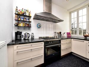 cocina con armarios blancos y fogones negros en Countryside Escape for 9, en Honnay