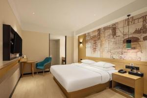 a hotel room with a large bed and a tv at City Comfort Inn Zhanjiang Middle Haibin Avenue Wanda Plaza in Zhanjiang