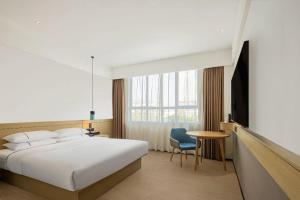 een slaapkamer met een bed, een tafel en een tv bij City Comfort Inn Zhoukou City Chuanhui District Huanghe Road in Zhoukou