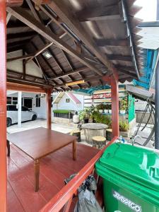 a patio with a wooden table and a green trash can at CILI PADI GUESTHOUSE in Kota Bharu
