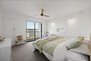 a white bedroom with a bed and a balcony at Casa Blanca Ventnor Beach in Ventnor