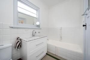 a white bathroom with a sink and a bath tub at Deco Days - Prahran in Melbourne +20 photos