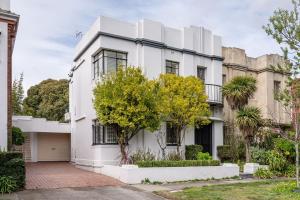 a white house with a tree in front of it at Deco Days - Prahran in Melbourne