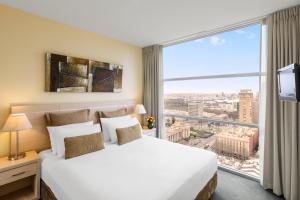 una camera d'albergo con un letto e una grande finestra di Oaks Melbourne on Lonsdale Suites a Melbourne