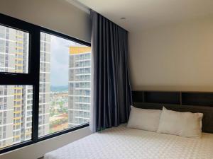 a bedroom with a bed and a large window at Shi House - Studios Building GH6 Near Vincom& Park in Long Bình